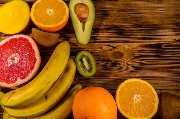 Still life with exotic fruits. Bananas, mango, oranges, avocado, grapefruit and kiwi fruits on rustic wooden table. Top view