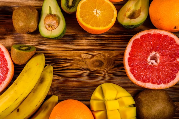 Still life with exotic fruits Bananas mango oranges avocado grapefruit and kiwi fruits on rustic wooden table Top view