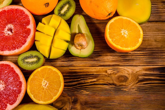 Still life with exotic fruits. Mango, oranges, avocado, grapefruit and kiwi fruits on rustic wooden table. Top view