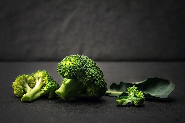 still life with fresh green broccoli on black stone plate