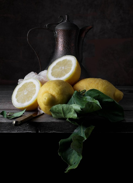 Photo still life with fresh lemons a vintage jug and a knife placed on the table