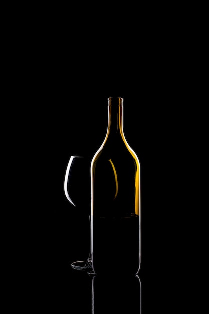 Still life with a glass of wine and a bottle on a black background