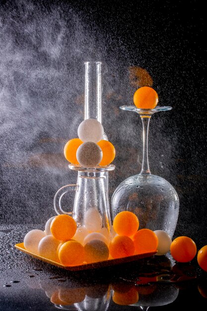 Still life with glasses and orange balls with water spray