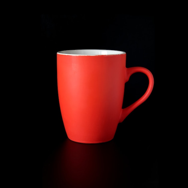 Still life with high red porcelain tea cup or coffee cup indoors studio shot isolated on black background front view close up