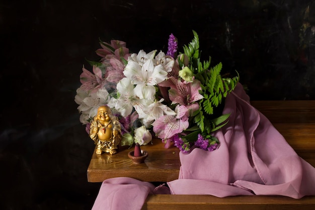 Still Life with laughing Buddha flowers and smoking incense