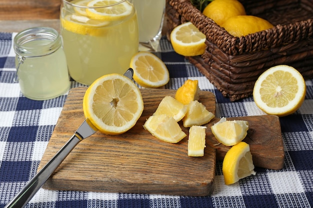 Still life with lemon juice and sliced lemons on wooden cutting board and napkin closeup