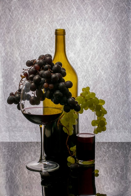 Still life with red wine in a glass and bottle and a bunch of ripe grapes