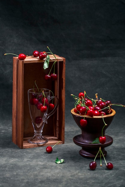 Still life with ripe red cherries with a vase and a glass