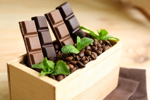 Still life with set of chocolate in wooden box of coffee grains on wooden background