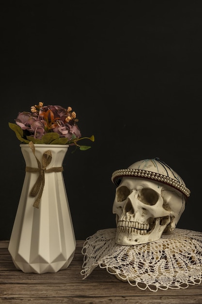 Photo a still life with a skull on a mat next to a vase with flowers