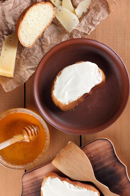 Photo still life with toasts with soft cheese honey and hard cheese on a wooden background simple breakfast with ricotta sandwich and honey healthy lifestyle