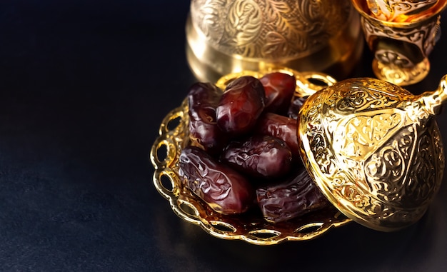 Still life with traditional luxury golden arabic coffee set with jezva, cup and dates. Ramadan concept.