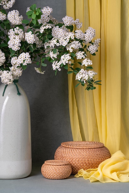 Still life with white flowers spirea Sprigs of white flowers in a brown vase on a gray background next to two round baskets Lots of places for text Postcard wishes