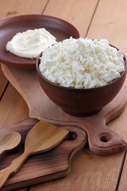 Still life on a wooden background Curd mass and cottage cheese on a clay plate on a wooden board Closeup of healthy breakfast food