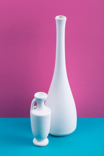 Stilllife with white vases on a colored background