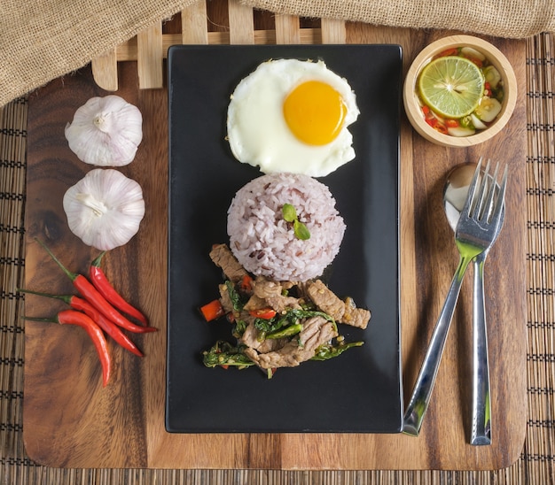 Stir-fried beef basil with fried egg and riceberry rice.