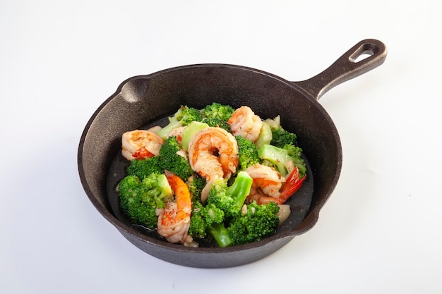 Stir fried broccoli and shrimp in a pan on a white background