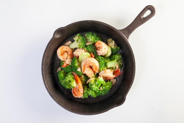 Stir fried broccoli and shrimp in a pan on a white background