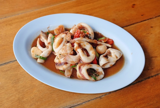 Stir fried squid with shrimp paste on plate on table background.