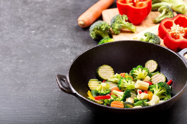 Stir fried vegetables in a wok on dark table