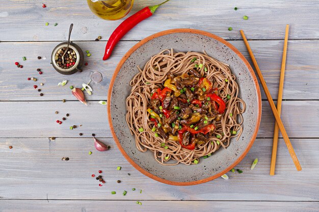 Photo stir fry from chicken hearts, paprika, onions and buckwheat noodles. top view