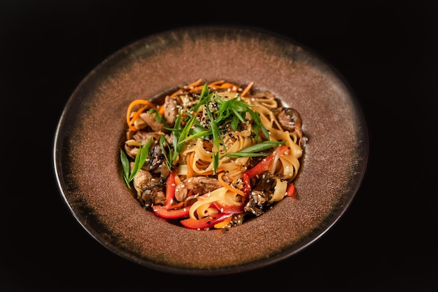 Stir fry noodles with vegetables and shrimps in black bowl Slate background Top view Copy space