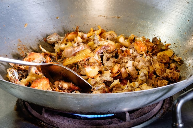 Stir frying chicken meat and garlic in steel wok with a spatula