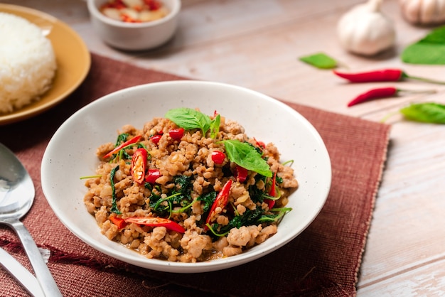 Stirfried basil with minced pork dish serving with rice and fish sauce on  wooden surface with copy space Thai street food