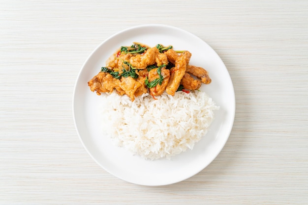 Stirfried fried fish with basil and chili in thai style topped on rice