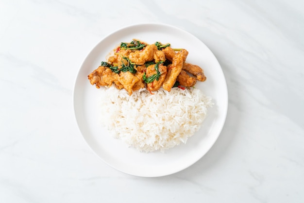 Stirfried fried fish with basil and chili in thai style topped on rice