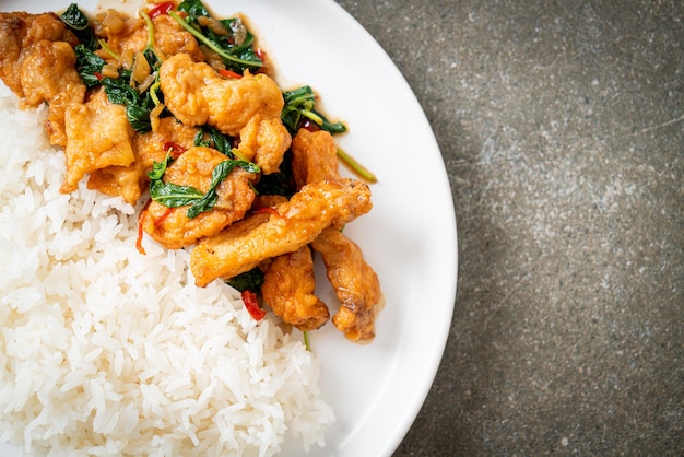 Stirfried fried fish with basil and chili in thai style topped on rice