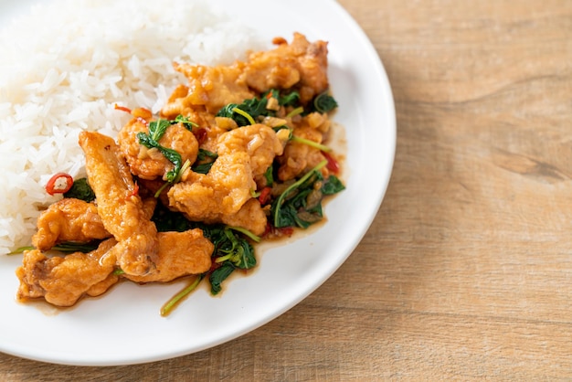 Stirfried fried fish with basil and chili in thai style topped on rice