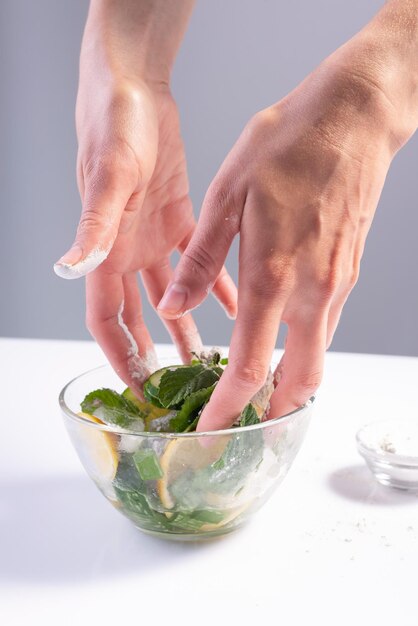 Stirring hands refreshing salad in glass plate on white background