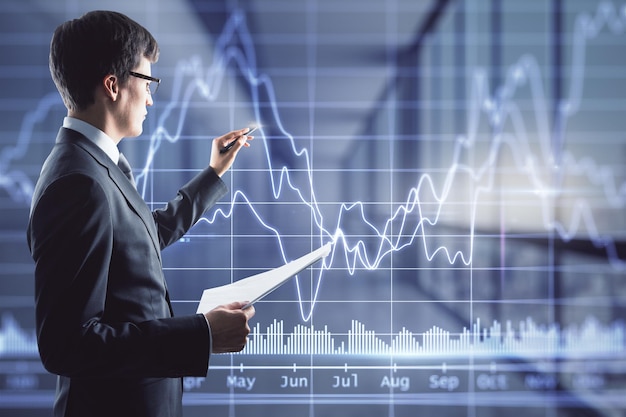 Stock market analyzing concept with trader writing on digital touch screen with financial chart