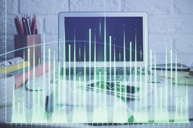 Photo stock market graph on background with desk and personal computer multi exposure concept of financial analysis