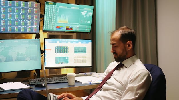 Stock market trader with suit and tie typing on laptop. Economy crash.