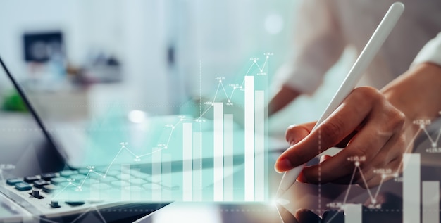 Stock market trading concept, hand using tablet and laptop with show analysis graph screen in the office.