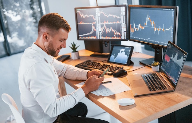 Stock market Young businessman in formal clothes is in office with multiple screens