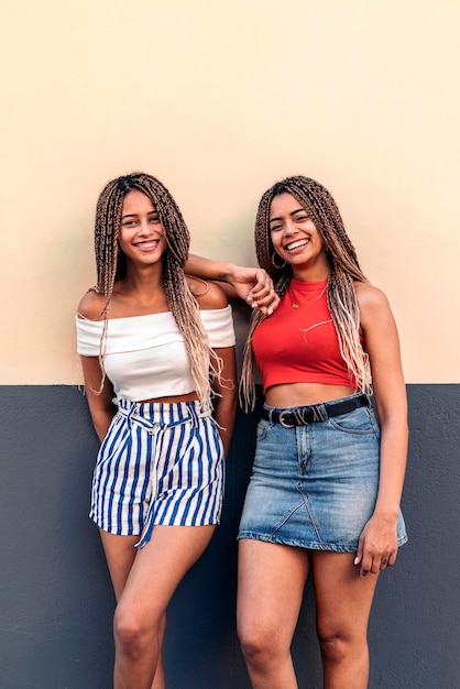 Stock photo of attractive african american sisters with cool braids smiling and looking at camera.