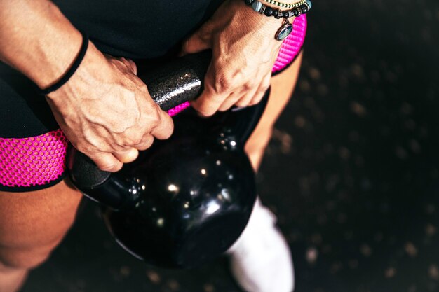 Photo stock photo of a detail of hands holding a kettlebell in the gym