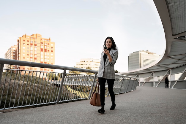 Stock photo of a young business woman typing on her phone She is walking on the street