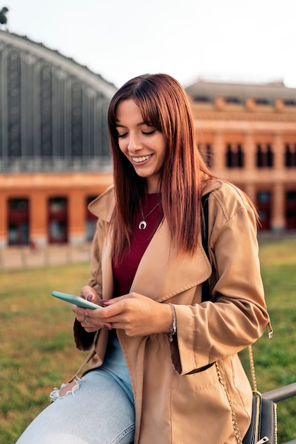 Stock photo of a young caucasian woman using her smartphone and smiling. She's texting.