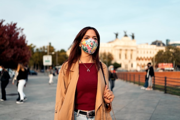 Stock photo of a young caucasian woman walking in the street. She's wearing a facemask due to covid19