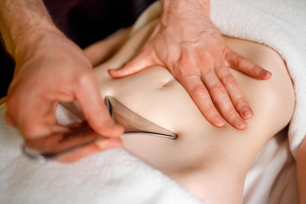 Stomach area massage with special metal instrument