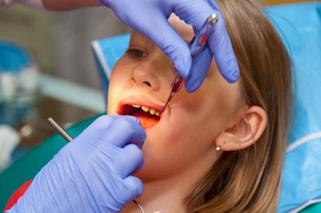 Stomatology checks up teeth for a child, girl on a reception for stomatology