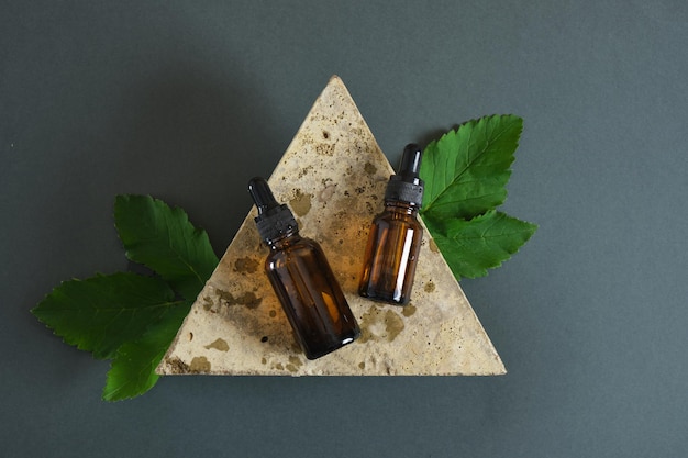 Photo stone, amber glass dropper bottles and mint leaves, peppermint oil in a bottle with pipette