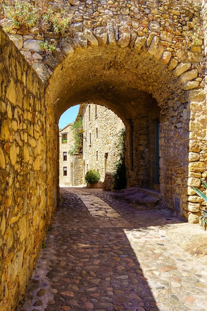 Stone arch in an alley with stone houses in the medieval town of Pals Girona