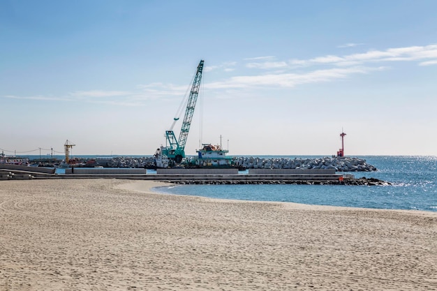 Stone breakwater on the sea with a sandy beach with construction machinery