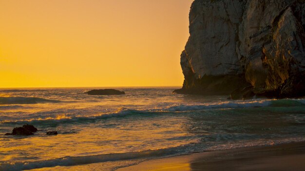 Stone cliffs Ursa beach rising over water surface at sunrise Calm ocean waves