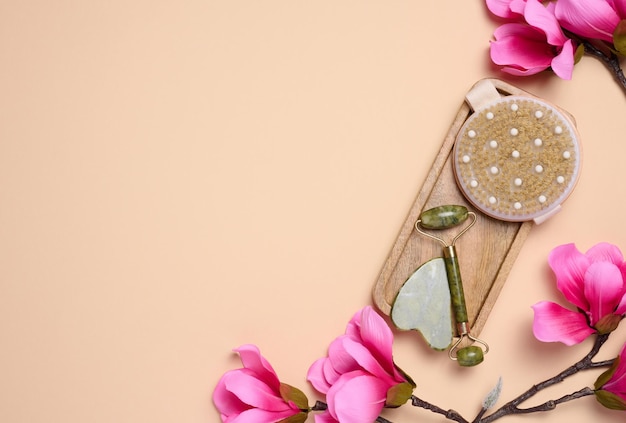 Stone face massager jade and a wooden body brush on a beige background top view